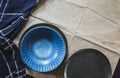 Empty vintage round dishes set on light brown cloth background. Styling with blue texture cloth