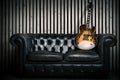 Empty vintage sofa and electric guitar with modern wood wall recording studio background. Music concept with nobody