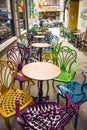 Empty vintage terrace in historical downtown with multi-colored chairs on the pavement sidewalk. Colorful chairs in retro