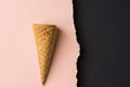 Empty waffle ice cream cone on dutone peachy pink black paper background with torn edge. Styled image mockup flyer poster