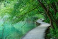 Empty walkway runs along the shore of a stunning emerald lake in Plitvice.