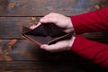 Empty wallet in hand. Male hands holding an empty wallet on a wooden background Royalty Free Stock Photo