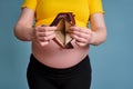 Empty wallet without money in the hands of a pregnant woman on a blue background Royalty Free Stock Photo