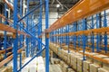 Empty warehouse interior with shelves, pallets, boxes and equipment.