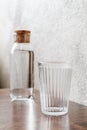 A empty water glass in front of an bottle Both are placed on wooden table