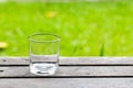 Empty water glass on wooden table with grass field background. Royalty Free Stock Photo