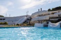 Empty water park with high white slides, pools and white sun loungers Royalty Free Stock Photo