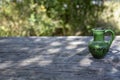 Empty weathered wood boards table, with a green ceramic vase, side view empty backdrop