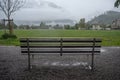 Empty wet metal bench in front of a green field at Interlaken with foggy mountain background Royalty Free Stock Photo