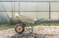 Empty wheelbarrow on the garden plot is on the rubble