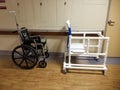 Empty wheelchair and bedside commode lined up in hospital hallway