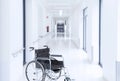 Empty wheelchair in modern hospital corridor interior in light colors. Soft blurred background Royalty Free Stock Photo