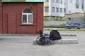 Empty wheelchair, a woman is sitting on a concrete slab, view from the back. The concept of poverty and disease. The photo