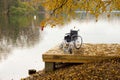An empty wheelchair on a wooden bridge near the river in the autumn park. The concept of accessibility of people with disabilities Royalty Free Stock Photo