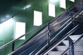 Empty white advertising urban billboard indoor in subway hall, vertical portrait, green walls, above metallic stairs. Royalty Free Stock Photo