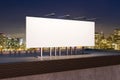 Empty white billboard banner on rooftop with city at night in the background. Outdoor advertisement and mock up concept. 3D