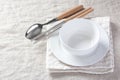 Empty white bowl with chopsticks and spoon with napkin on linen tablecloth background