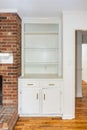 An empty white built in bookcase in a living room next to a red brick fireplace Royalty Free Stock Photo