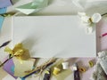 Empty white canvas, art materials, fresh flowers, decor on a light background Royalty Free Stock Photo