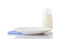 Empty white ceramic plate on blue napkin in small white polka dots and glass of milk