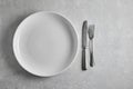 Empty white ceramic plate and fork and knife on gray stone table. Top view with a copy of the space Royalty Free Stock Photo