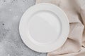 Empty white ceramic plate on gray concrete background with linen cloth. Minimal tableware mockup with copy space Royalty Free Stock Photo