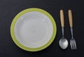 Empty white ceramic plates with spoons and forks arranged on an old black wooden table - top view Royalty Free Stock Photo