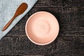 An empty white clay bowl and a wooden spoon on a gray cloth napkin on an old wooden table surface Royalty Free Stock Photo