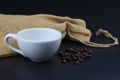 Empty white coffee cup with coffee bean and bag on black color background. Royalty Free Stock Photo