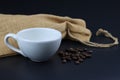 Empty white coffee cup with coffee bean and bag on black color background. Royalty Free Stock Photo