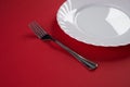 Empty white dinner plate with silver fork and Dessert Tablespoon isolated on red tablecloth background with copy space. Table Set Royalty Free Stock Photo