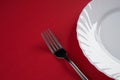 Empty white dinner plate with silver fork and Dessert Tablespoon isolated on red tablecloth background with copy space. Table Set Royalty Free Stock Photo