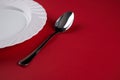 Empty white dinner plate with silver fork and Dessert Tablespoon isolated on red tablecloth background with copy space. Table Set Royalty Free Stock Photo