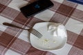 empty white dish with leftovers of eaten food, crumpled table-napkin and steel fork