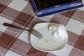 empty white dish with leftovers of eaten food, crumpled table-napkin and steel fork