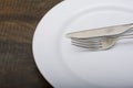 Empty white dish with spoon and fork on wood table Royalty Free Stock Photo