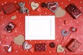 Empty white frame with gifts, hearts and other love objects on red background. Valentine`s day concept Royalty Free Stock Photo