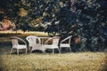 Empty and white garden table and chairs in a garden in autumn. Royalty Free Stock Photo