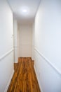 An empty white hallway in a house with stained hardwood floors Royalty Free Stock Photo