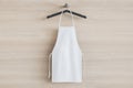 Empty white kitchen apron on hangers. Light wood background. Chef and cooking concept. 3D Rendering Royalty Free Stock Photo