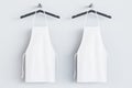 Empty white kitchen aprons on hangers. Light background. Chef and cooking concept. Mock up place. Royalty Free Stock Photo
