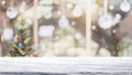 Empty white mable stone table top on blur with bokeh Christmas tree and new`s year decoration on window background with snowfall Royalty Free Stock Photo