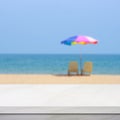 Empty white marble table over blur blue sky and sea beach with colorful umbrella in summer background, product display montage Royalty Free Stock Photo