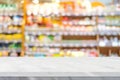 Empty white marble table over blur product shelf at grocery supermarket in shopping mall background, for product display Royalty Free Stock Photo