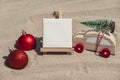 Empty white paper note frame with copy space for your text or design displays on sandy beach. Christmas balls car with Royalty Free Stock Photo