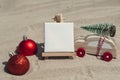 Empty white paper note frame with copy space for your text or design displays on sandy beach. Christmas balls car with Royalty Free Stock Photo