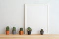 Empty white photo frame and cute cactus pots mockup on wooden table with white wall background copy space. Creative ideas Royalty Free Stock Photo