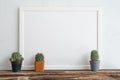 Empty white photo frame and cute cactus pots mockup on wooden table with white wall background copy space. Creative ideas Royalty Free Stock Photo