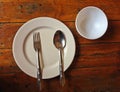 Empty white plastic dish with spoon and fork on old wooden background Royalty Free Stock Photo