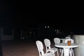 An empty white plastic summer table on the summer promenade, around a few chairs. Lunch party